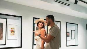 Een stel in een kunstgalerie, met ingekaderde kunstwerken aan de muren.
