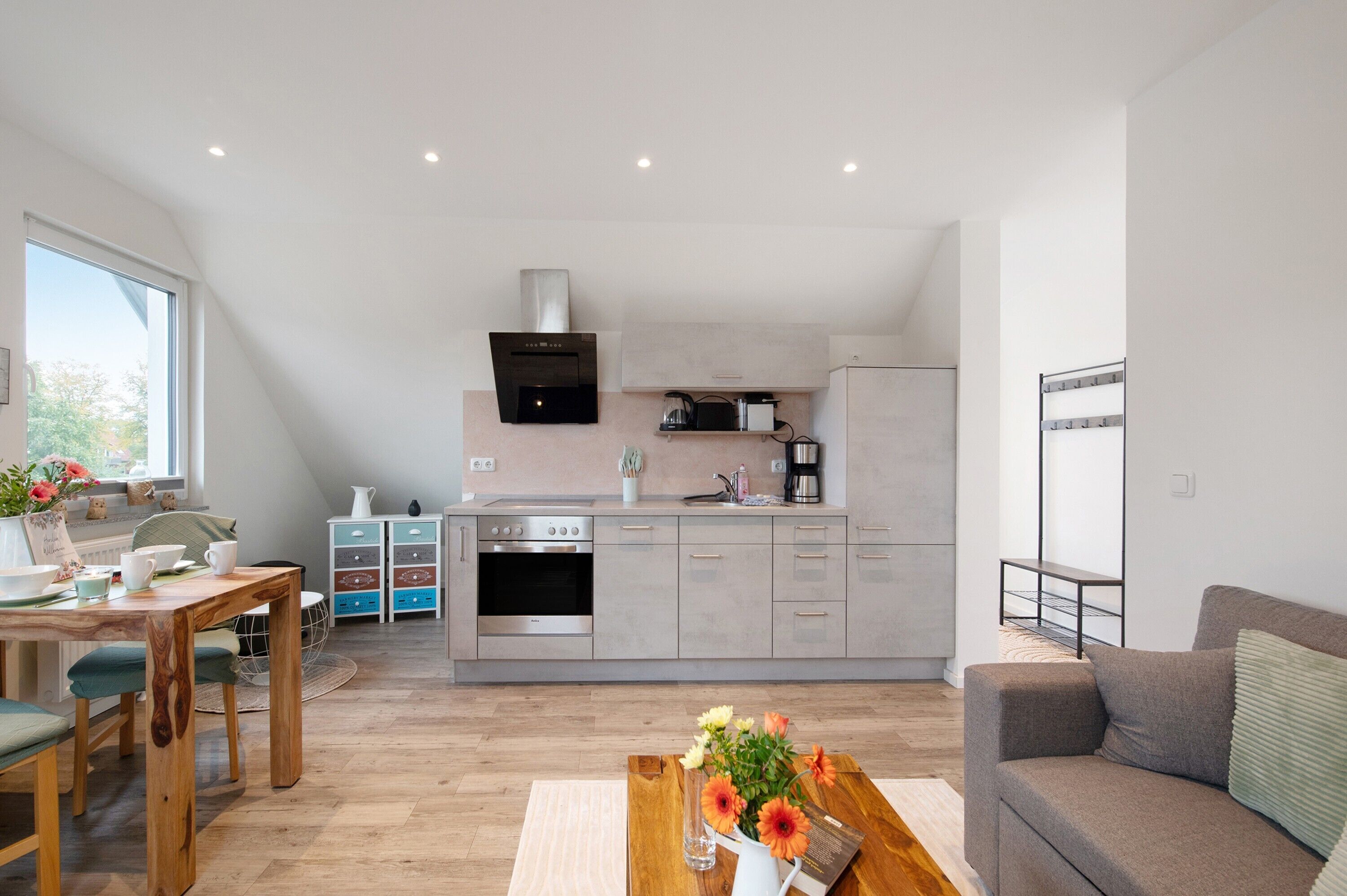 A modern kitchen with a built-in oven, a coffee machine, and a kettle on the countertop.