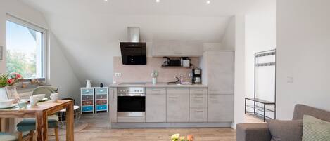 A modern kitchen with a built-in oven, a coffee machine, and a kettle on the countertop.