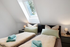 Une chambre avec deux lits, un puits de lumière, des lampes de chevet et une vue sur les arbres.