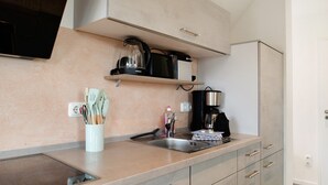 A modern kitchen with a built-in stove, a coffee maker, and utensils on the counter.