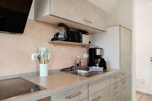 A modern kitchen with a built-in stove, a coffee maker, and utensils on the counter.