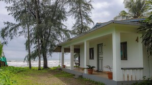 Ein Küstenhaus mit einer Veranda, Topfpflanzen und Blick auf den Ozean.