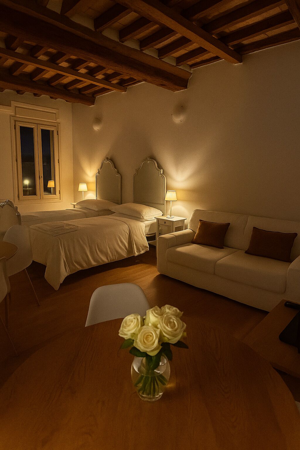 A bedroom with a bed, bedside tables, a sofa, and a vase of flowers.