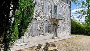 A stone building with a balcony, a table with chairs, and a gravel area. - Guest Room 'Domaine du chemin Royale' with Shared Terrace, Shared Garden, and Wi-Fi (Saint-Germain)