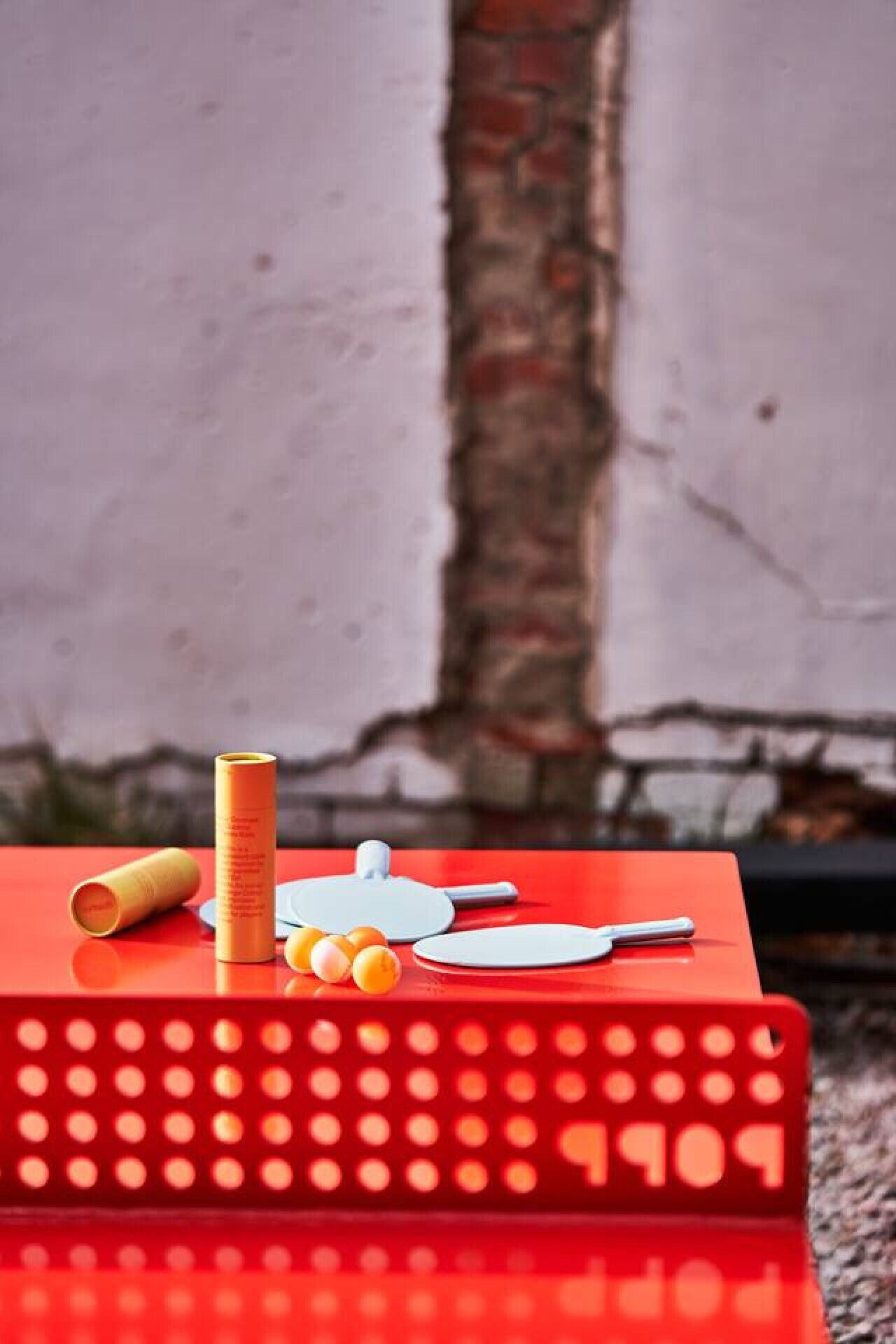 A red table with a white object on top, a yellow cylindrical object, and some small round objects.