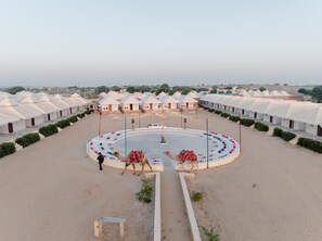 A desert resort with multiple tents arranged in rows, a central circular area with seating, and camels. - The Royal Sam Desert Camp (Jaisalmer)