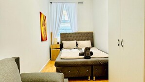 Un dormitorio con cama, mesita de noche, silla y armario.