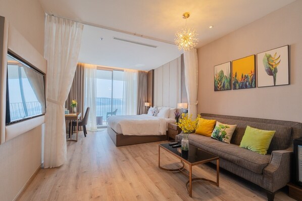 Moderni hotellihuone, jossa on suuri sänky, sohva, ruokailutila ja taideteoksia seinällä.