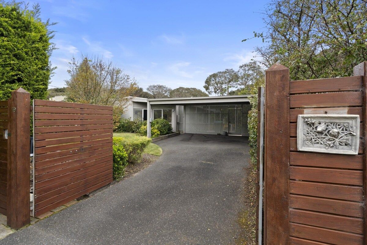 A gated driveway leading to a modern house with a garage.