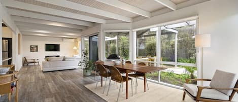 Un vaste espace de vie doté d’un plancher en bois, d’une table à manger et d’un canapé.