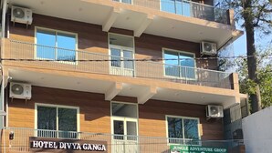 Ein mehrstöckiges Gebäude mit einem Schild für 'Hotel Divya Ganga' und 'Jungle Adventure Group'.