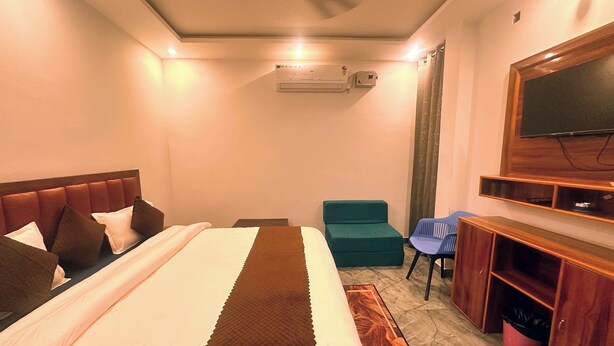 Ein Hotelzimmer mit einem Bett, einem Schreibtisch, einem Sessel, einem Fernseher und einer Klimaanlage.
