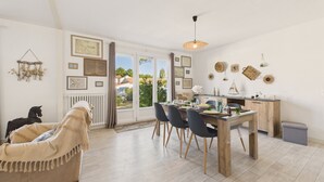 Un coin repas avec une table en bois, des chaises et une vue sur l’extérieur, accessible par une porte vitrée.