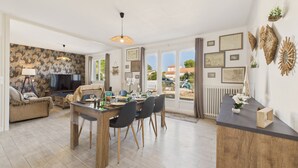 Un salon spacieux comprenant un coin repas, de grandes fenêtres et une vue sur l’extérieur.