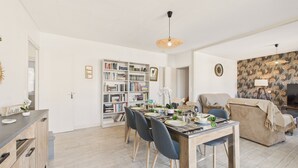 Un salon moderne comprenant un coin repas, une bibliothèque et un espace salon confortable.