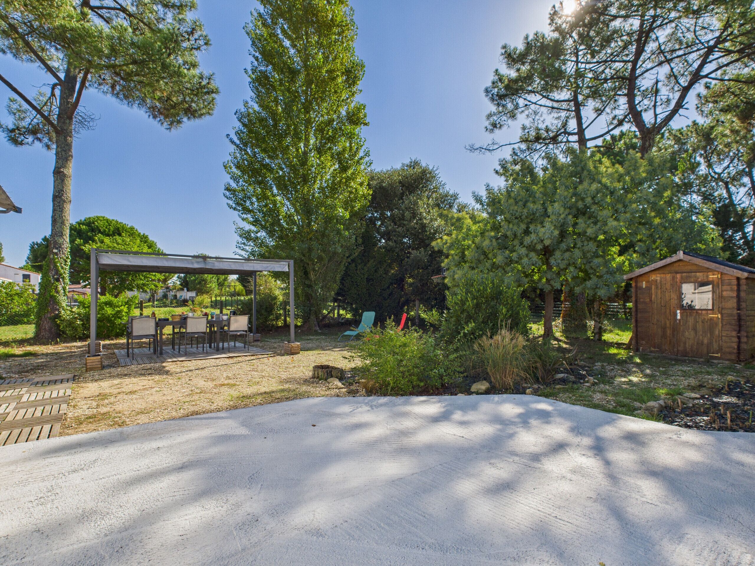 Un patio couvert avec des meubles d’extérieur, un abri en bois et une terrasse en béton.