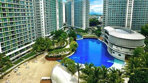 Ein Hochhotel mit zahlreichen Balkonen, einem zentral gelegenen Pool und üppiger Bepflanzung.