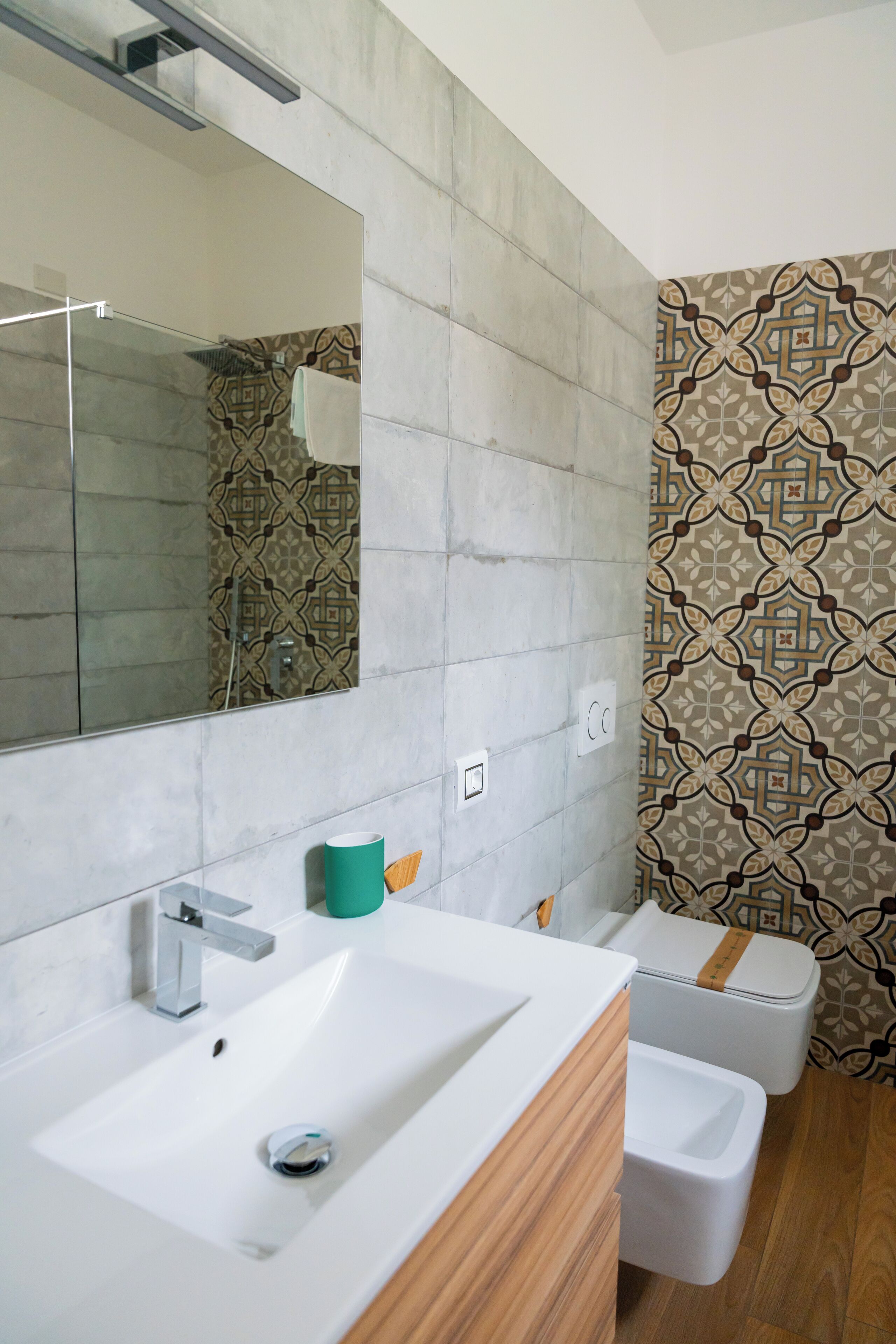 A modern bathroom with a large mirror, white sink, and two toilets.