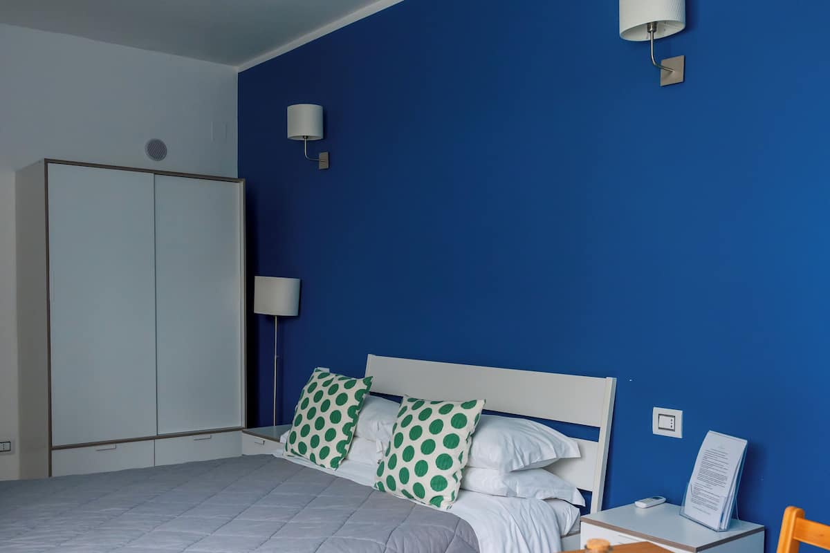 A bedroom with a bed, a wooden table, and chairs.