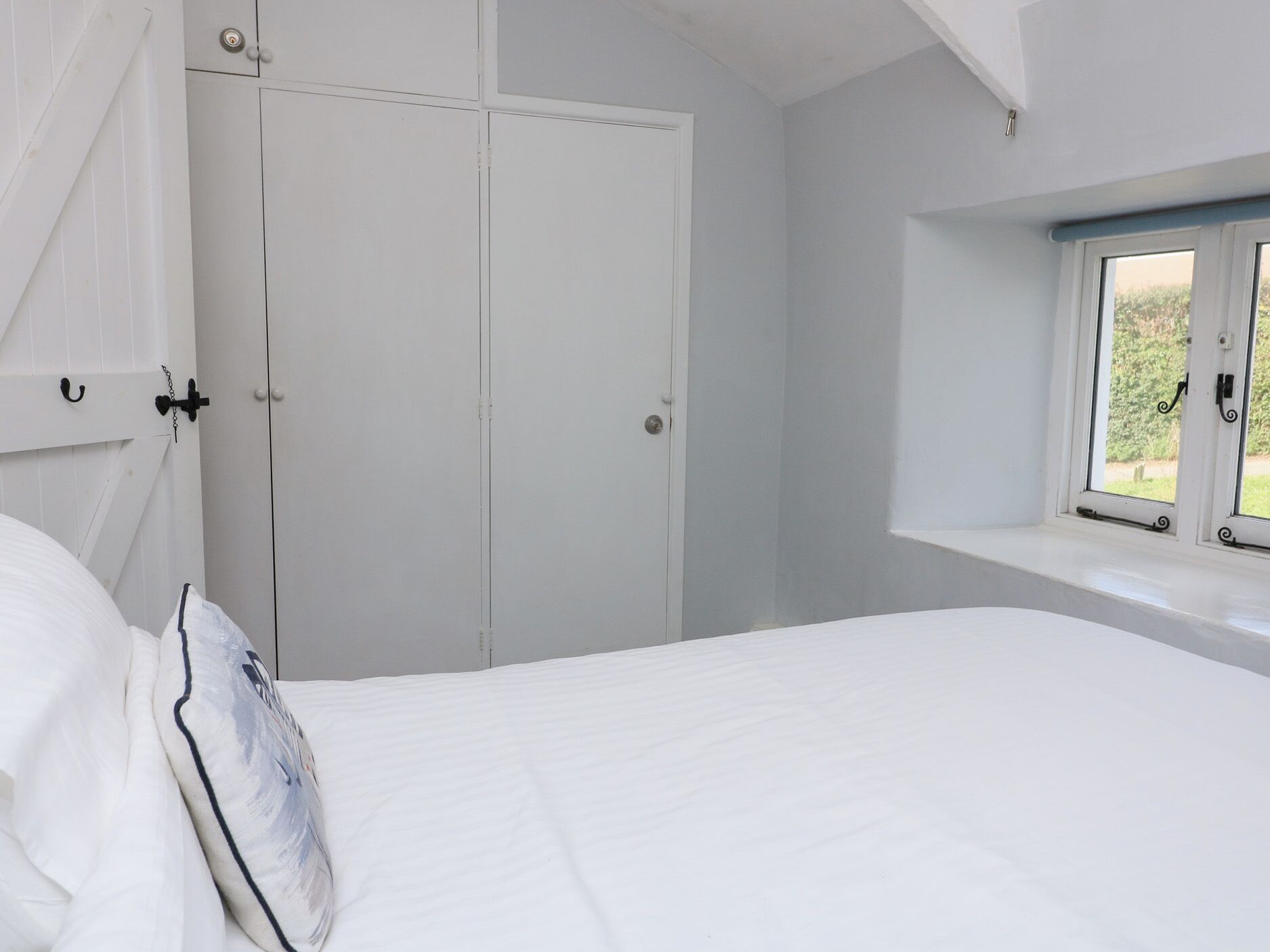 Ein Schlafzimmer mit Bett, Fenster mit Blick und Kleiderschrank.