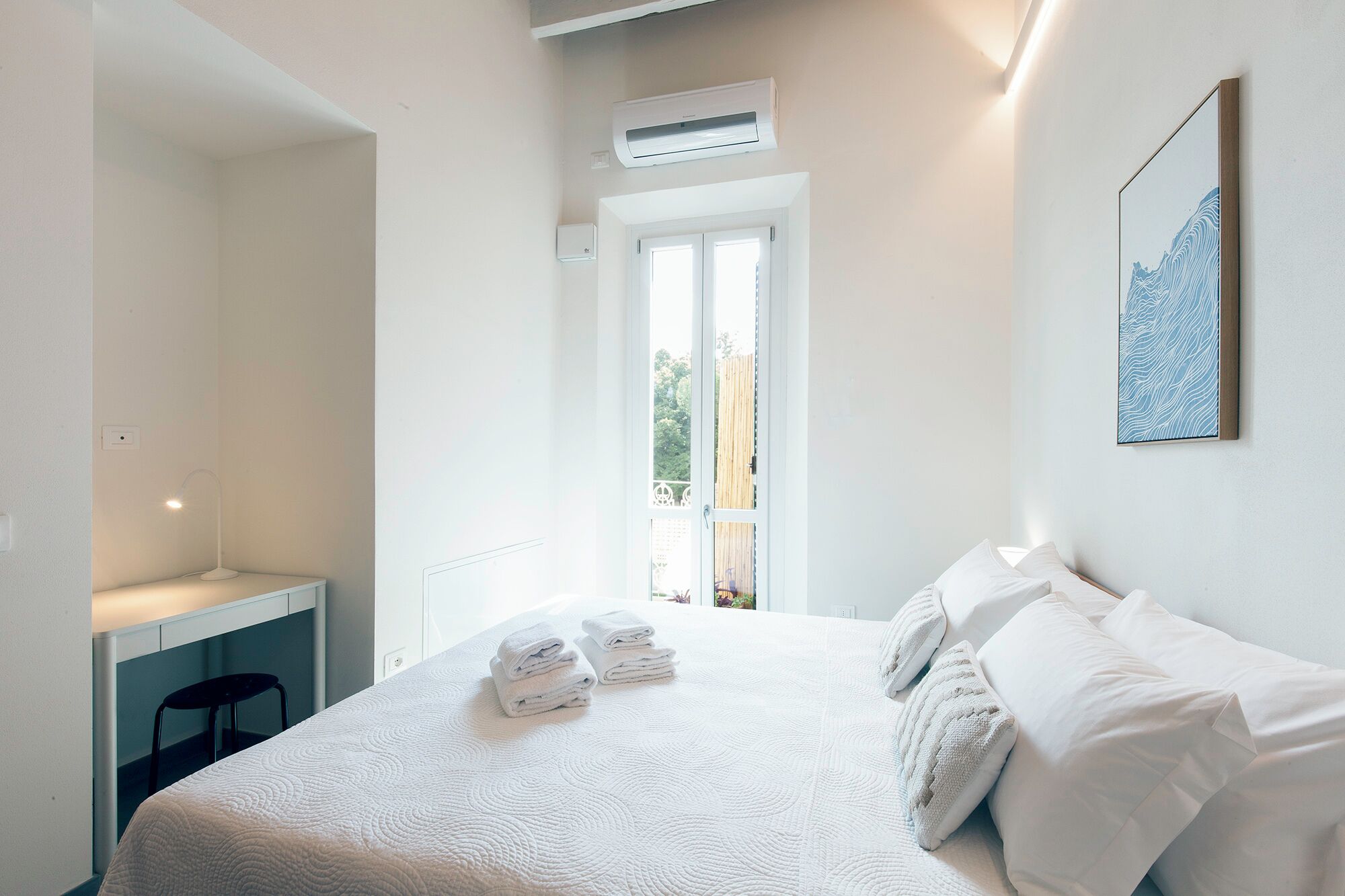 Une chambre à coucher comprenant un lit, un bureau et un appareil de climatisation.