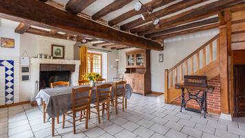A dining area with a table set for four, a fireplace, and a staircase leading to an upper level.