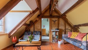 Une pièce mansardée chaleureuse avec un plafond en pente, un banc en bois, un canapé et une bibliothèque.