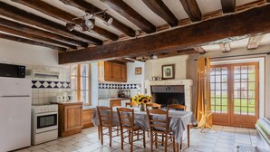 Une cuisine avec des poutres en bois, une table à manger avec des chaises, un réfrigérateur et une cuisinière.