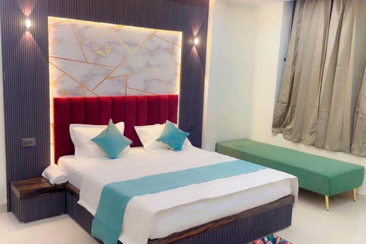 A modern bedroom with a large bed, a red headboard, and a green bench.