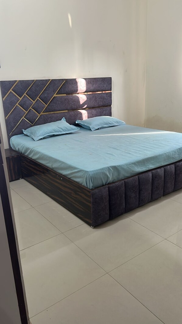 A bed with a headboard featuring a geometric pattern, a light blue bedspread, and a dark upholstered footboard. - Hotel Sultan Paradise (Roorkee)