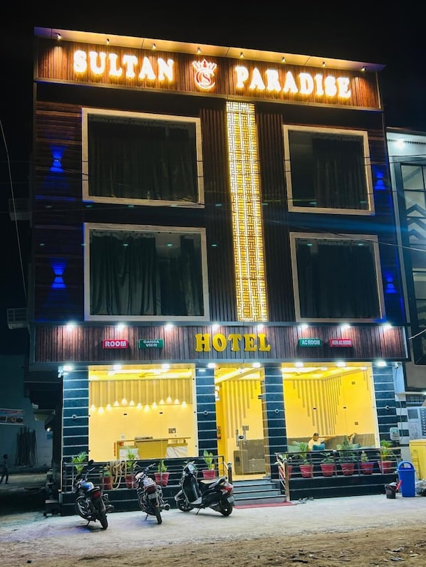 A hotel named "Sultan Paradise" with a prominent sign, multiple windows, and a visible entrance with a yellow facade.