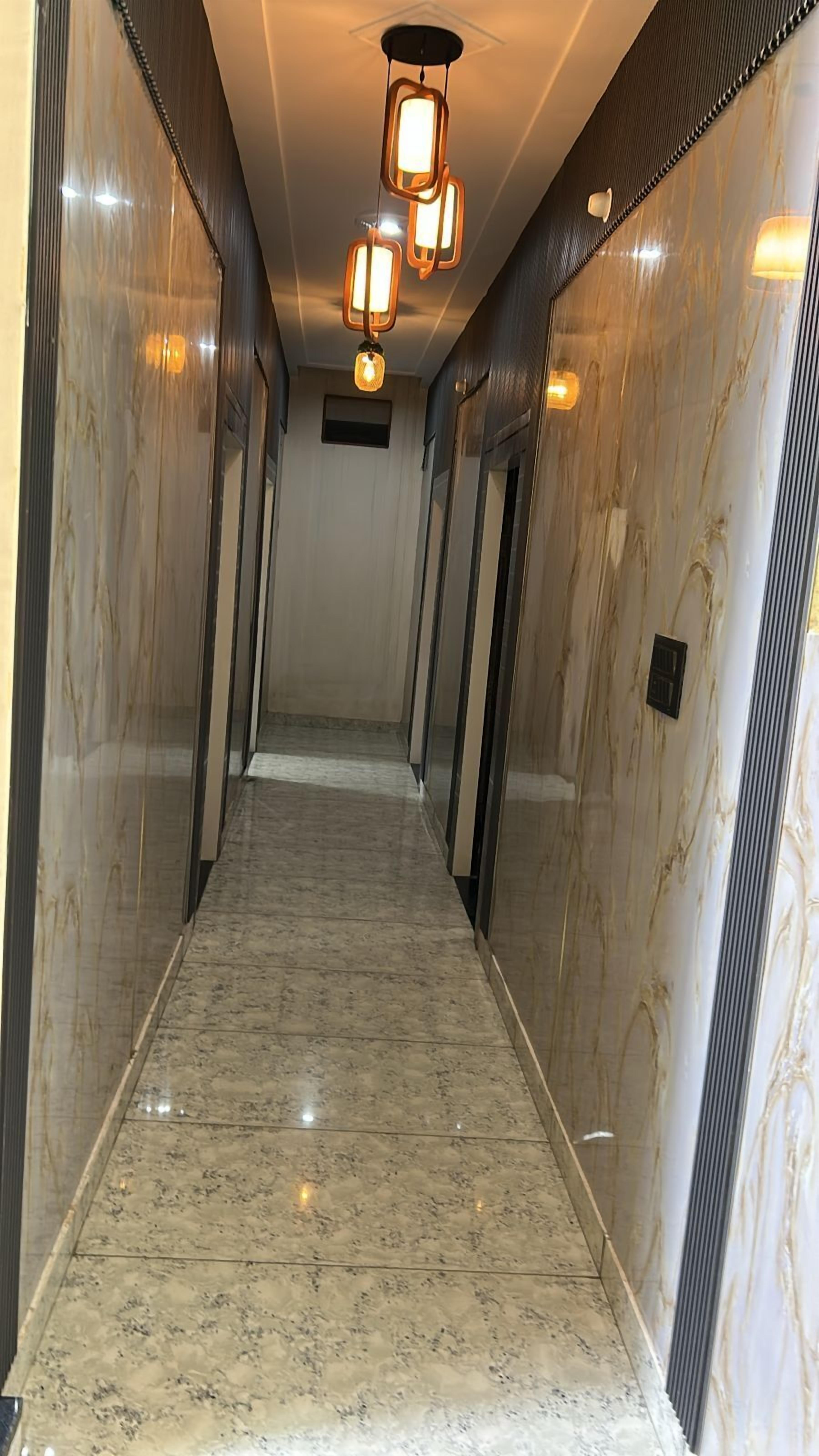 A marble-floored hallway with modern light fixtures and mirrored walls.