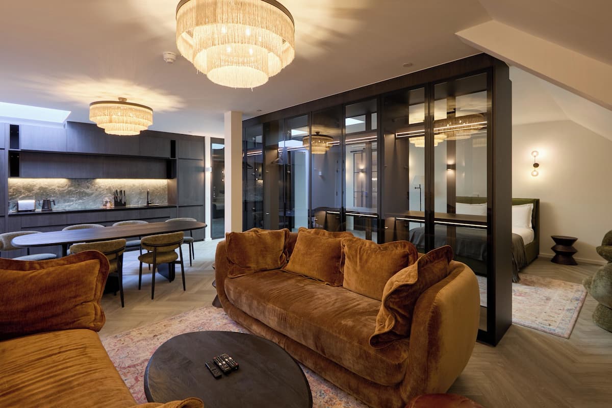 Ein modernes Wohnzimmer mit einem großen braunen Sofa, einem Essbereich und einer Küche mit Marmorfliesenspiegel.