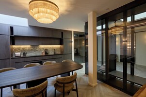 Una cocina moderna con una mesa y sillas de madera oscura, un candelabro y un separador de vidrio.