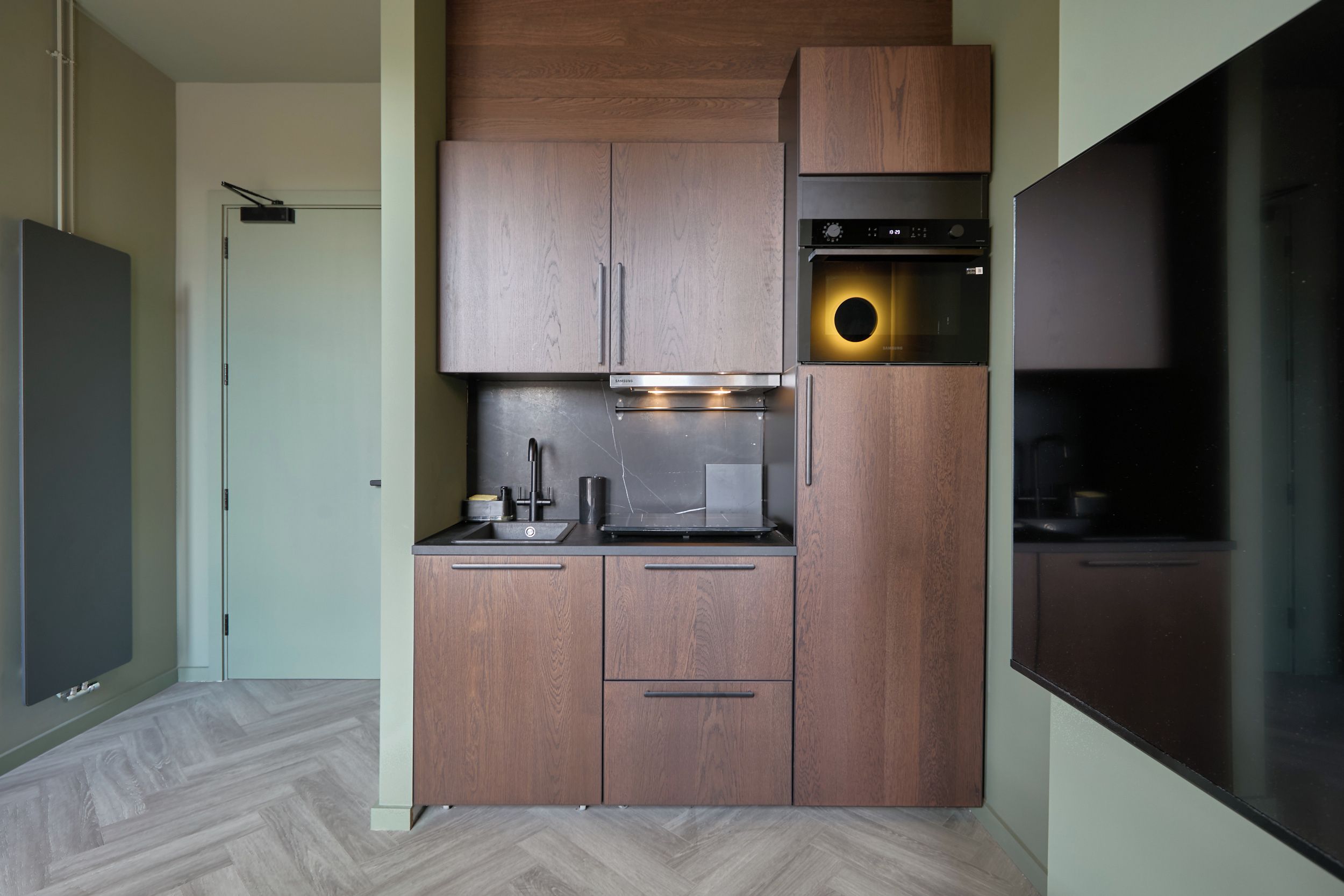 A compact kitchen with a built-in oven, a microwave, and a sink.