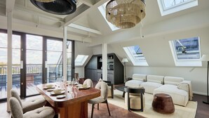 Amplio apartamento tipo loft con comedor, sofá y un gran ventanal con vistas a un balcón.