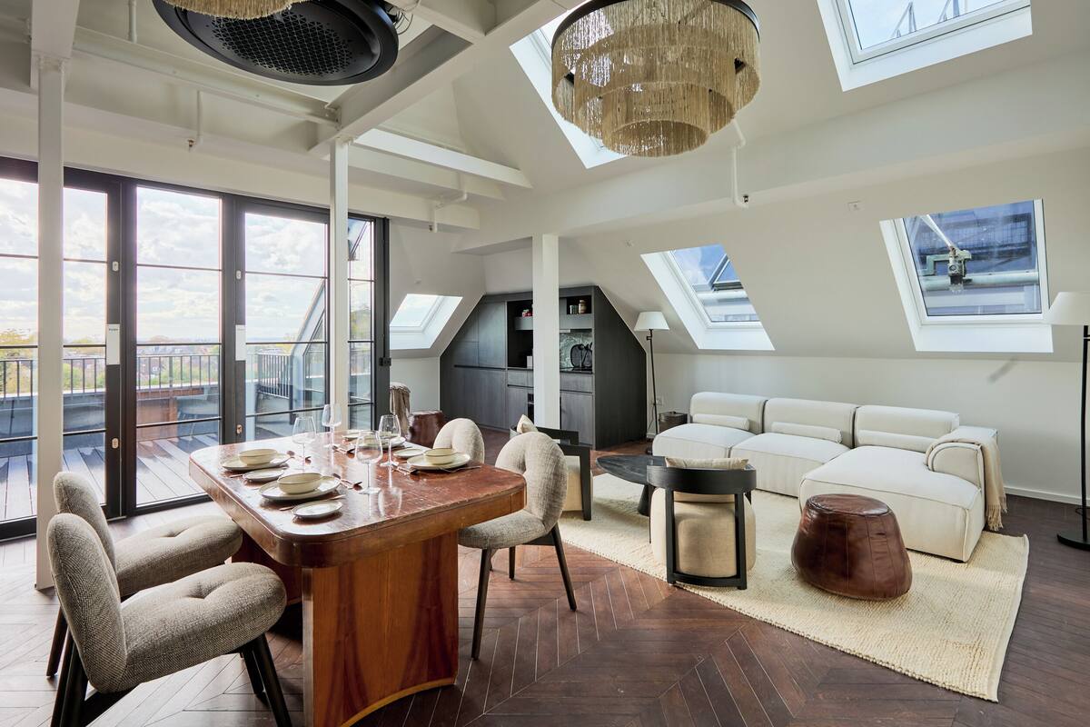 Ein großzügiges Loft mit Essbereich, einer Couch und einem großen Fenster mit Balkonblick.