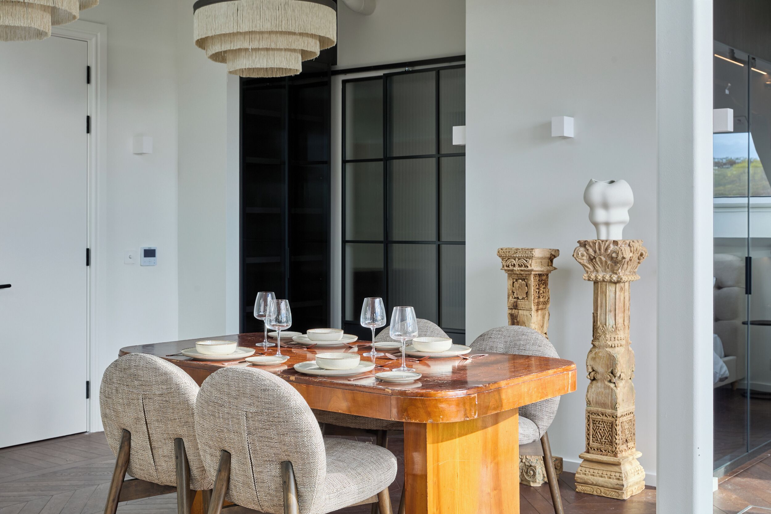A dining area with a wooden table set for six, surrounded by upholstered chairs.