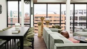 Un interior moderno con zona de comedor, sofás y ventanas amplias con vistas a la ciudad.
