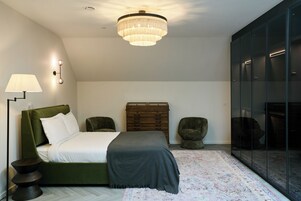 Un dormitorio con cama, cómoda, silla, lámpara y candelabro.