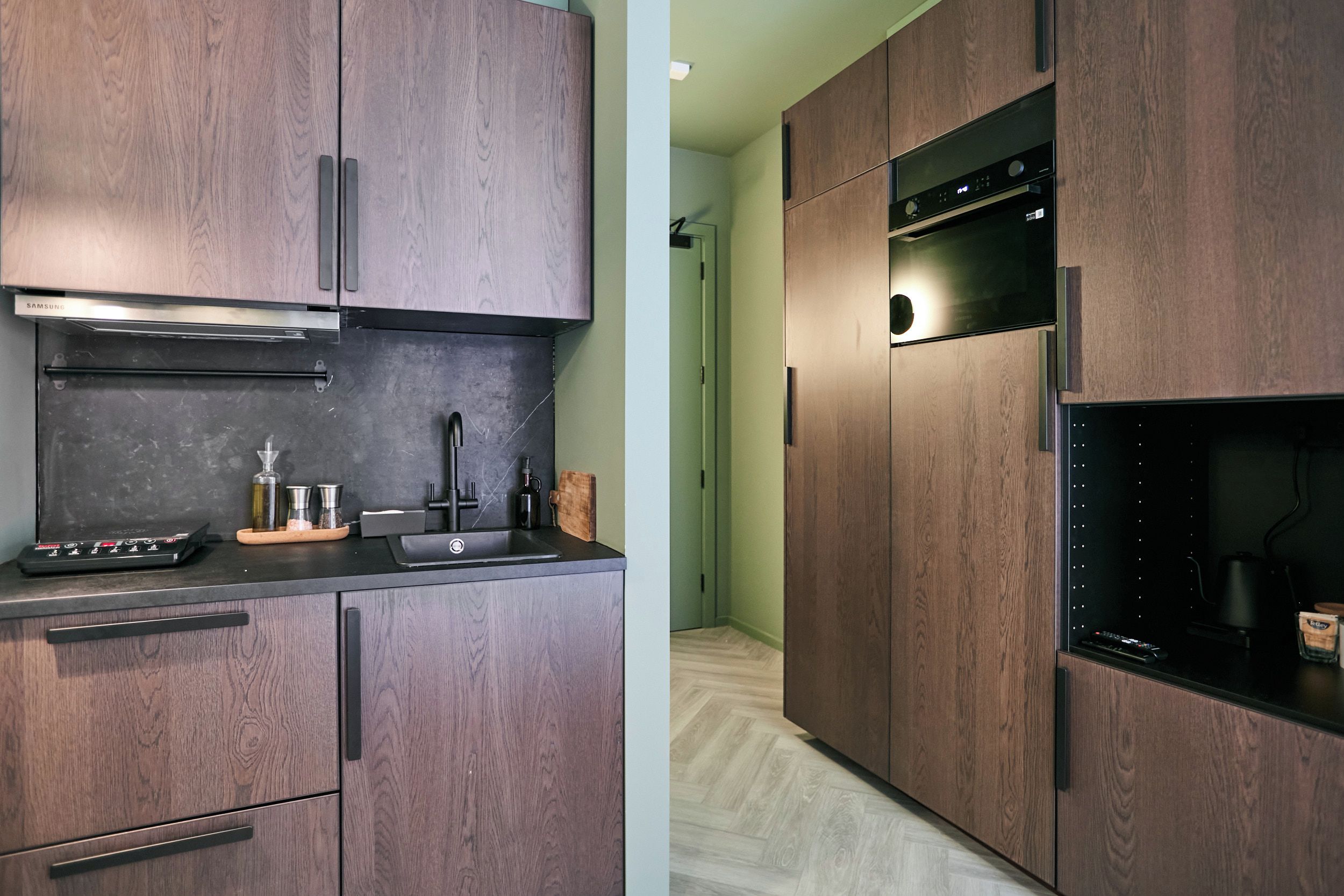 A modern kitchen with dark wood cabinetry, a stainless steel range hood, and a built-in oven.