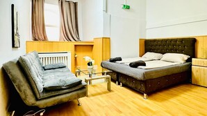 A room with a bed, a sofa, a glass table, and a radiator.