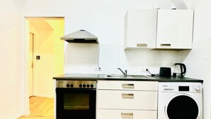 A compact kitchen with a stove, oven, sink, and washing machine.
