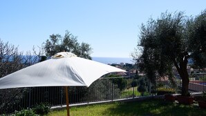 A grassy area with two white lounge chairs and a large white umbrella. - Villa Camilla App Garden (Diano Castello)