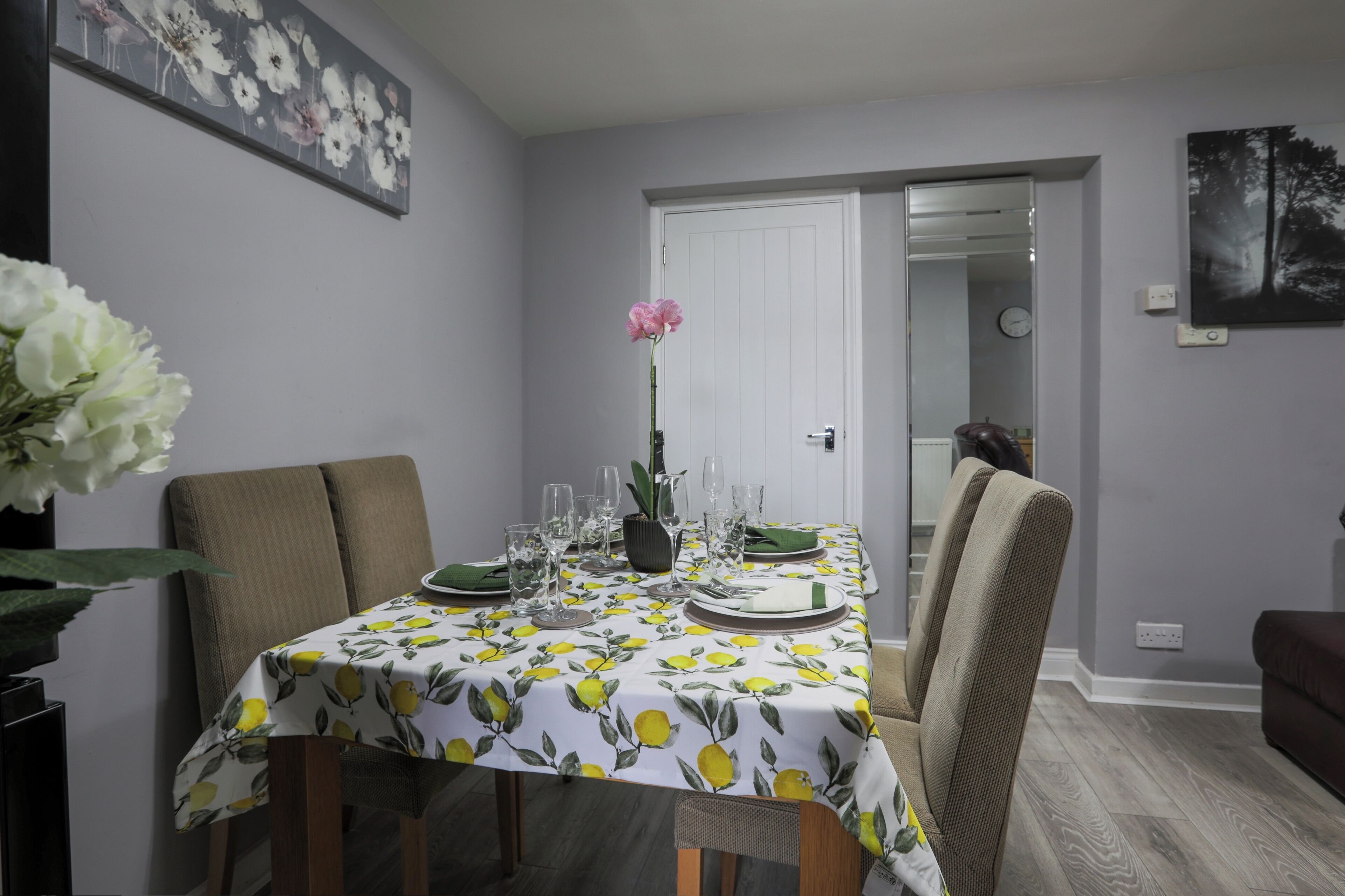 Comedor con una mesa dispuesta para cuatro, con mantel floral y servilletas verdes.