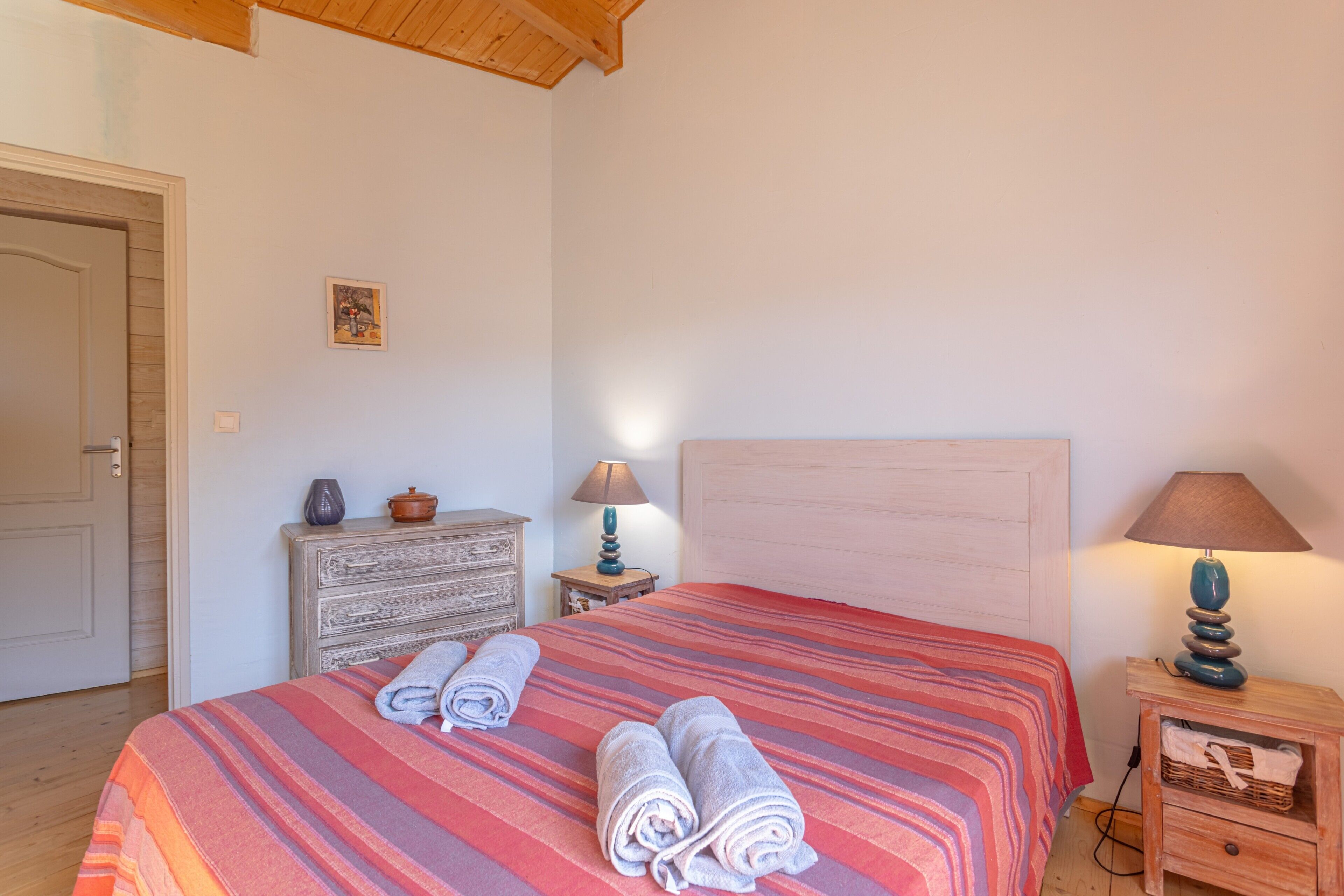 Ein Schlafzimmer mit einem Bett, zwei Nachttischen, einer Kommode und einer Tür.