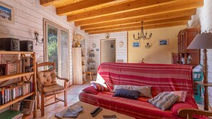 A cozy cabin interior with a red-striped sofa, wooden bookshelves, and a wooden ceiling. - Gîte Madres Coronat Balcon du Canigou (Jujols)