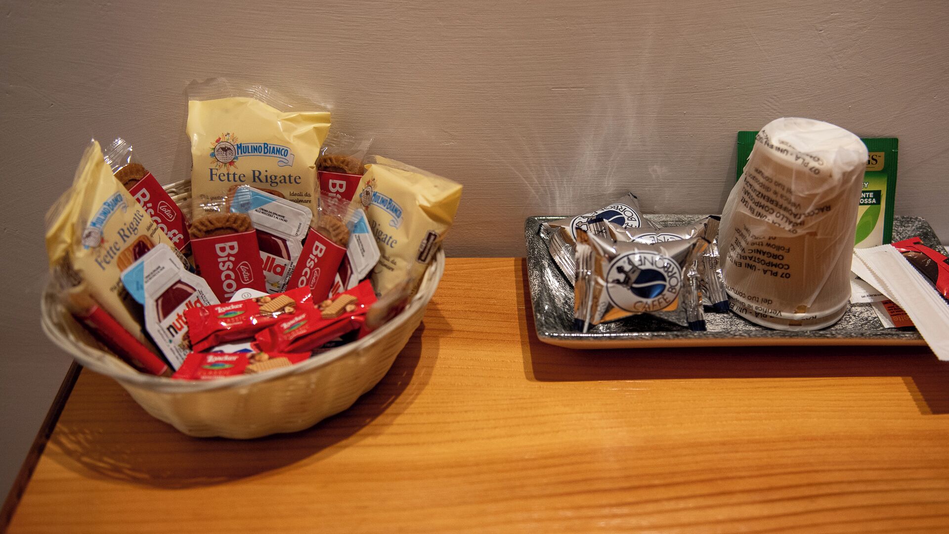 A table with a bowl of assorted packaged snacks and a plate with a coffee creamer and a packet of coffee.