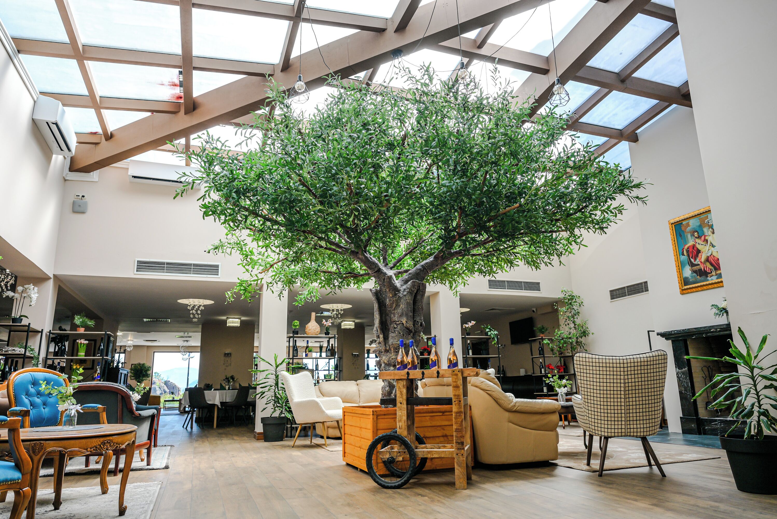 Un espacio interior amplio con un gran árbol artificial, arreglos de asientos y un techo alto con tragaluces.